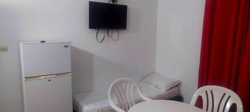 a kitchen with a table and a chair and a refrigerator at Residence Yasamine Ain El Turck in 'Aïn el Turk