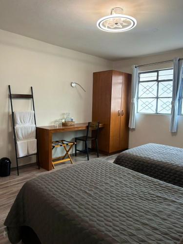 a bedroom with two beds and a desk and a desk at El salto de Camela Hostal in Uruapan del Progreso