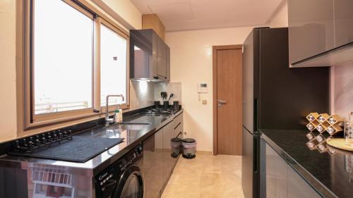 a kitchen with a sink and a black refrigerator at Piscine chauffée - Sauna - Hammam - Appart Coeur de Gueliz in Marrakech