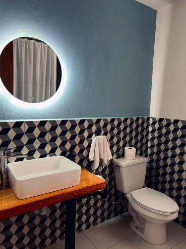 a bathroom with a toilet and a sink and a mirror at El salto de Camela Hostal in Uruapan del Progreso