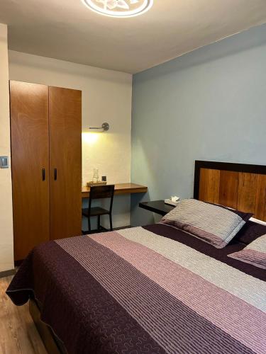 a bedroom with a bed and a desk with a desk at El salto de Camela Hostal in Uruapan del Progreso
