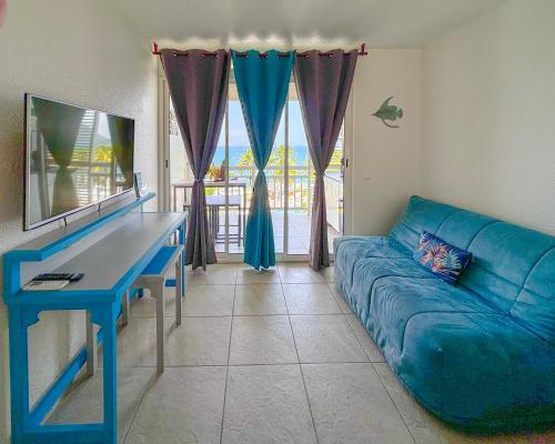 a living room with a blue couch and a blue desk at Studio Ti Saphir in Le Diamant