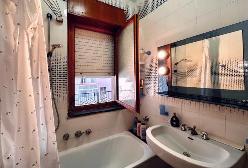 Un baño con bañera, lavabo y espejo. en Alfa Holidays, en Sorrento