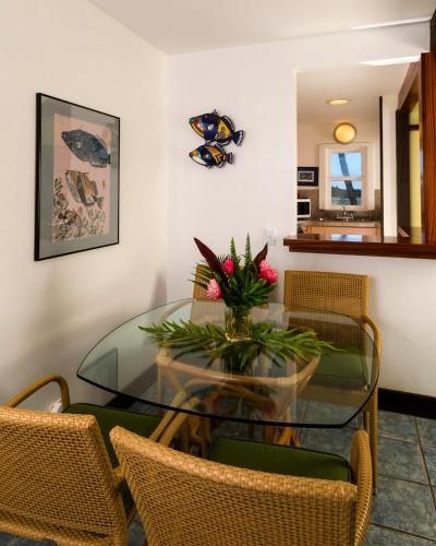 a glass dining room table with chairs and a vase of flowers at Hana Kai Maui - #104 Haneoʻo in Hana