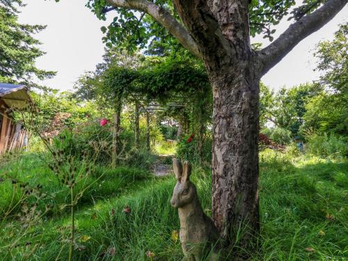 a rabbit sitting next to a tree at Little Timbers in Ringwood