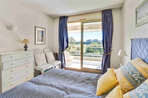 une chambre avec un lit, une chaise et une fenêtre dans l'établissement T3 in Mandelieu with Terrace AC Parking Swimming Pool Tennis - BENAKEY, à Mandelieu-la-Napoule