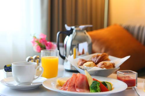 a table with plates of food and a cup of orange juice at ANA Crowne Plaza Kobe by IHG in Kobe