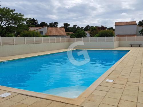 une piscine avec de l'eau bleue dans une cour dans l'établissement Pavillon 4/5 pers. avec piscine à 1,4 km de la plage Belesbat, Saint Vincent sur Jard - FR-1-357-327, à Saint-Vincent-sur-Jard
