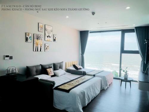 a bedroom with a large bed and a large window at Flamingo Hải Tiến - Căn góc 2 Phòng - View 2 mặt biển in Thanh Hóa