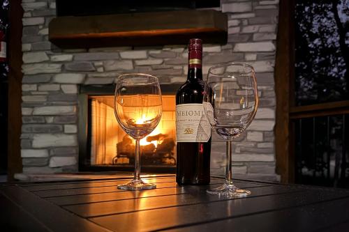 a bottle of wine and two glasses on a table with a fireplace at Meadows Edge Cabin in Broken Bow