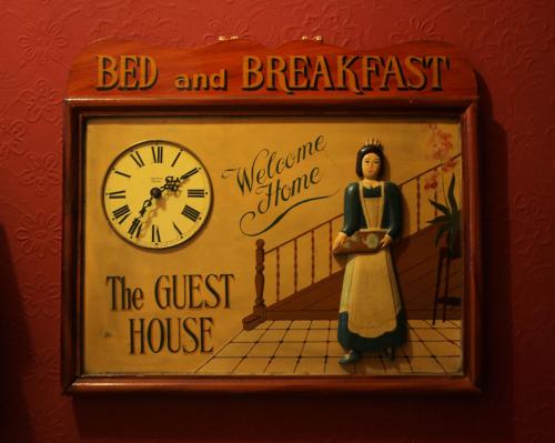 a clock on a wall with a doll in a frame at Atticus Central Guest House in Aberdeen