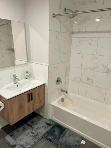 a white bathroom with a sink and a tub and a mirror at Luxury Stay for NYC visit Jersey City 7 Min Walk NYC Train Station in Jersey City