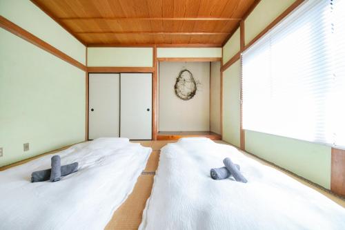two white beds in a room with a window at 湯河原「ゲストハウス城堀の家」 in Yugawara