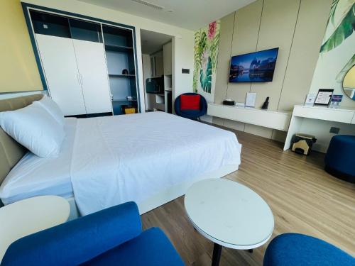 a bedroom with a white bed and blue chairs at FLAMING0 Ibiza Hải Tiến Resort in Thanh Hóa