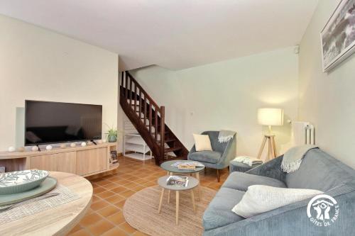 un salon avec un canapé bleu et une télévision dans l'établissement Du moulin de kerlann, à Plumergat