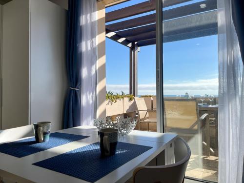 une salle à manger avec une table et une vue sur un balcon dans l'établissement Saint-Cyprien : Appt front de mer avec piscine, parking et clim - FR-1-753-25, à Saint-Cyprien