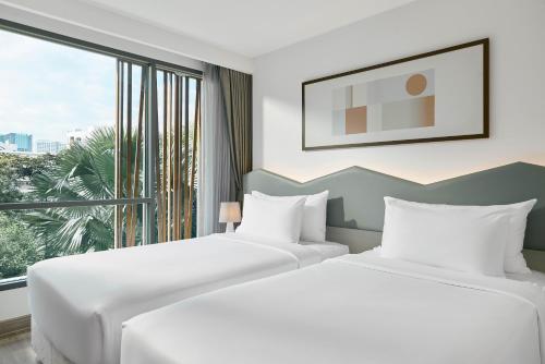two beds in a hotel room with a window at Livable Hotel Bangkok in Bangkok
