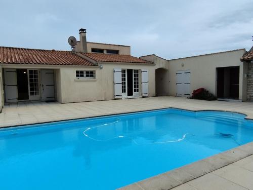 une grande piscine bleue devant une maison dans l'établissement Maison oléronaise avec piscine, jardin clos et à 1km de la plage de Foulerot - FR-1-778-30, à Saint-Georges-dʼOléron