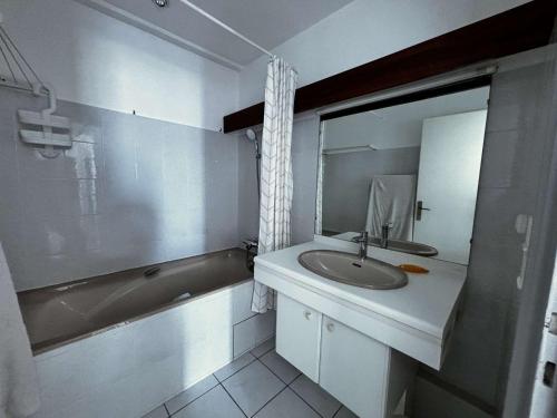 une salle de bain avec un lavabo, une baignoire et un miroir dans l'établissement Appartement pour 5 personnes avec WiFi et parking à Royan - FR-1-494-197, à Royan