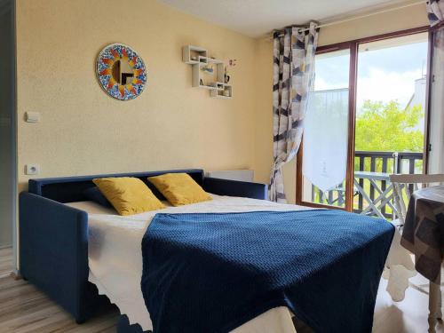 a blue bed with yellow pillows in a bedroom at Charmant T2 à 300m de la plage en Normandie – Balcon, parking et local vélo inclus - FR-1-788-21 in Varaville