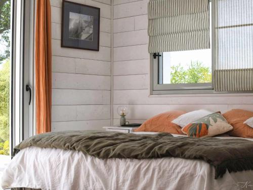 une chambre avec un lit avec des oreillers et une fenêtre dans l'établissement Maison rénovée, proche océan, calme, terrasses et jardin – La Forêt-Fouesnant - FR-1-481-166, à La Forêt-Fouesnant