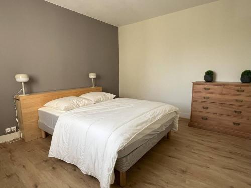 une chambre avec un grand lit et une commode dans l'établissement Appartement T2 lumineux avec balcon, parking et proche centre-ville – 4 pers - FR-1-392-240, au Pouliguen