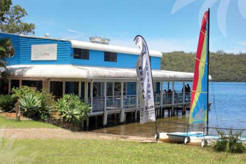 a building on the water with flags in front of it at Araluen in Smiths Lake