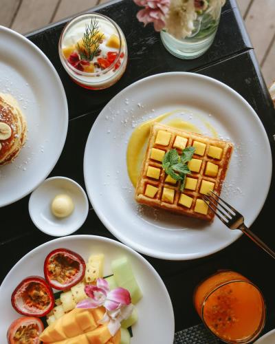 a table topped with plates of waffles and other food at The Naka Island, a Luxury Collection Resort & Spa, Phuket in Ko Naka