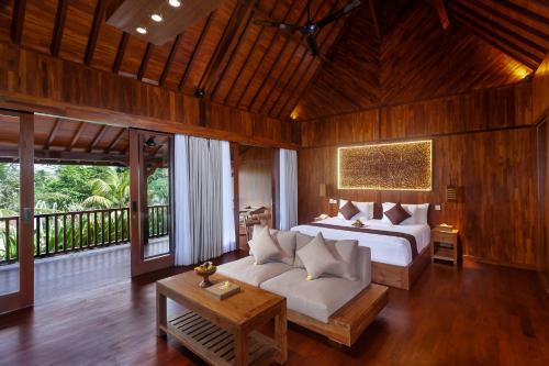 a bedroom with a bed and a couch in a room at Manah Shanti Suites by Pramana Villas in Ubud