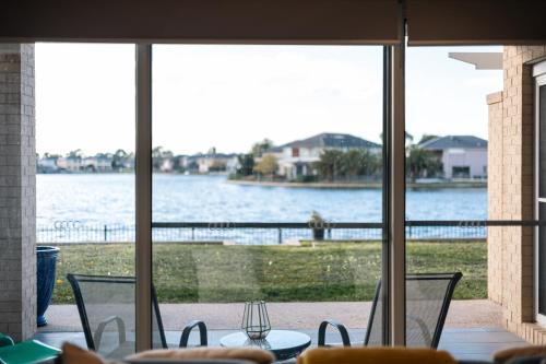 a view of the water from a patio with a table and chairs at Luxury Waterfront Villa in Sanctuary Lakes in Point Cook