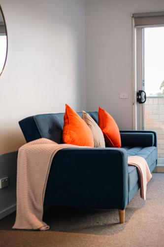 a blue couch with orange pillows on it at Luxury Waterfront Villa in Sanctuary Lakes in Point Cook