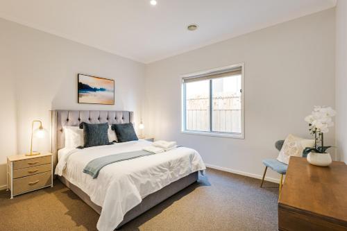 a bedroom with a bed and a desk and a window at Luxury Waterfront Villa in Sanctuary Lakes in Point Cook