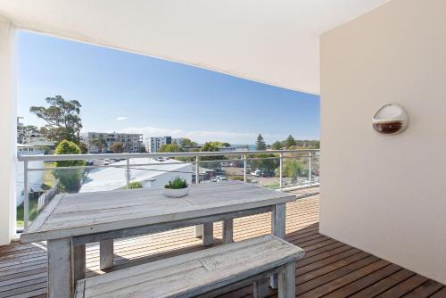 a wooden table on a balcony with a view at Cote D'Azure, 13 61 Donald Street - Lovely unit air con, Wi-Fi, secure parking, complex lift and pool in Nelson Bay