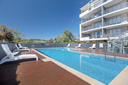 a swimming pool with chairs next to a building at Cote D'Azure, 13 61 Donald Street - Lovely unit air con, Wi-Fi, secure parking, complex lift and pool in Nelson Bay