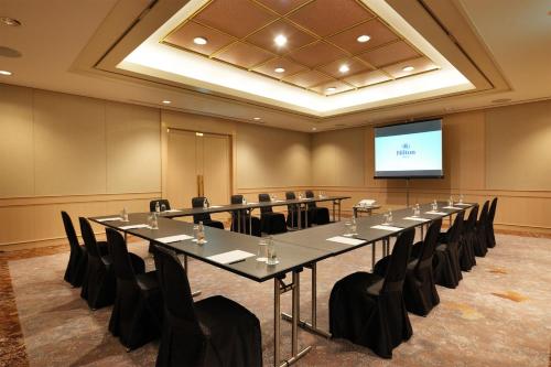 a conference room with a large table and chairs and a screen at Hilton Nagoya Hotel in Nagoya