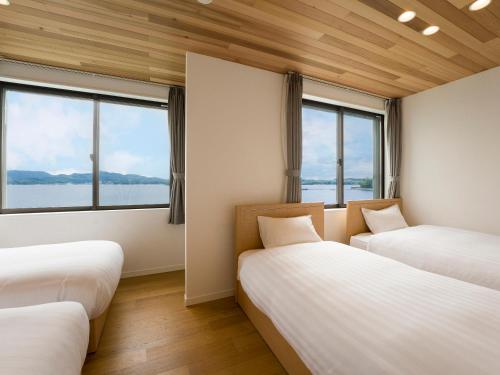 two beds in a room with large windows at Rakuten STAY HOUSE Amakusa in Yanagi