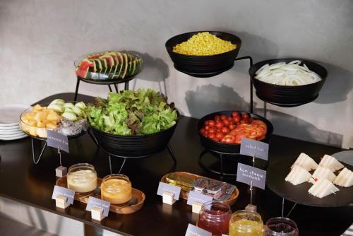 a display of food on a table with bowls of vegetables at Livable Hotel Bangkok in Bangkok