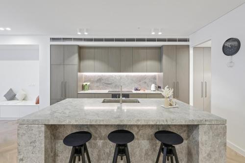 a kitchen with a large counter with two stools at Stanley Lane Residence Darlinghurst in Sydney