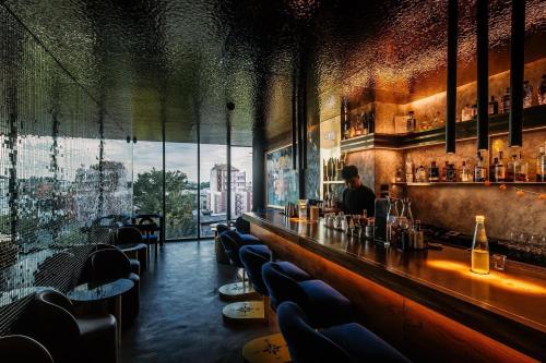 a man sitting at a bar in a restaurant at Art Mai Gallery Nimman Hotel Chiang Mai - SHA Plus in Chiang Mai