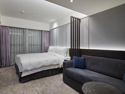 a hotel room with a bed and a couch at The Tango Hotel Taipei Linsen in Taipei