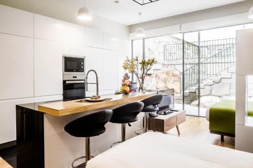 a kitchen with white cabinets and a kitchen island with black chairs at Oportolazaro Premium Downtown Porto in Porto