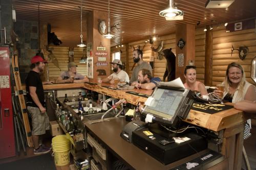a group of people standing around a bar at The Raging Elk Adventure Lodging in Fernie