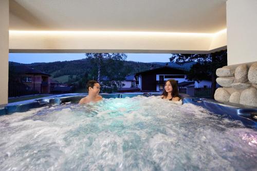 a man and a woman in a hot tub at EveRest Apartamenty Szczyrk in Szczyrk