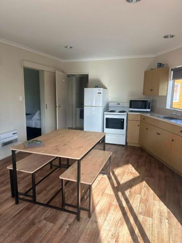 a kitchen with a wooden table and a refrigerator at Pohara Beach TOP 10 Holiday Park in Pohara