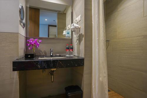 a bathroom with a sink and a mirror at BATIQA Hotel Palembang in Palembang