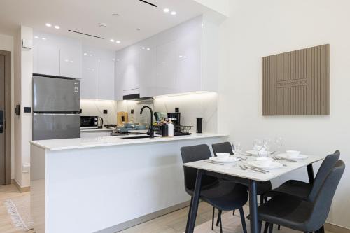 a white kitchen with a table and chairs at 1-Bed in Binghatti Crescent, Next to Circle Mall in Dubai