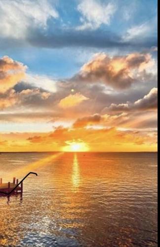 a sunset over the ocean with a boat in the water at Key Largo Paradise in Key Largo