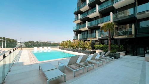 a swimming pool with chairs next to a building at 1-Bed in Binghatti Crescent, Next to Circle Mall in Dubai