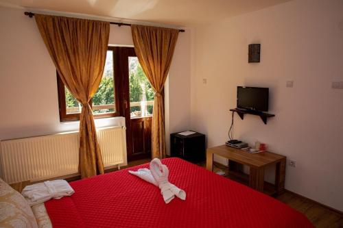a hotel room with a red bed with towels on it at Pensiunea Alma Lepsa in Lepşa