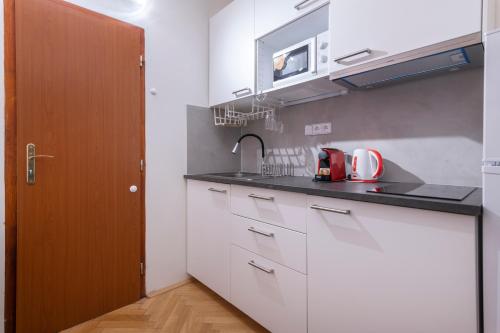 Una cocina con gabinetes blancos y un fregadero. en Historic Spirit at Studio under the Prague Castle, en Praga